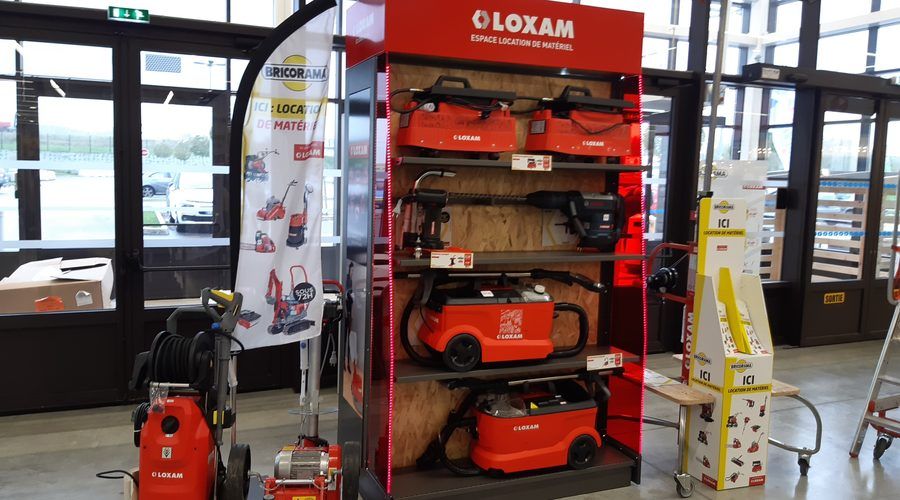 Un corner de location Loxam dans un magasin de bricolage, nettoyeurs et aspirateurs rouges en rayon