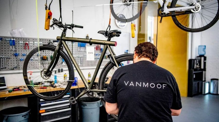 Un réparateur VanMoof au travail dans un atelier, un vélo sur le pied d'atelier