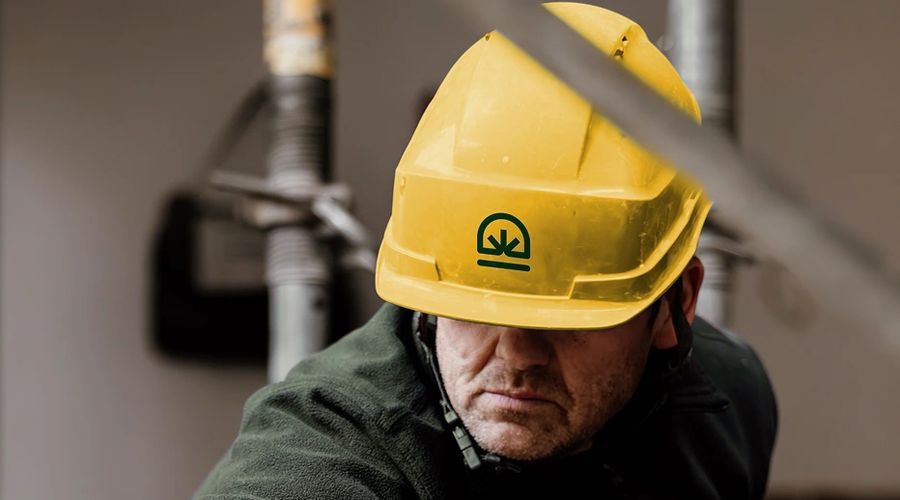 Un technicien Le Bon Tuyau en casque de chantier, sur une canalisation