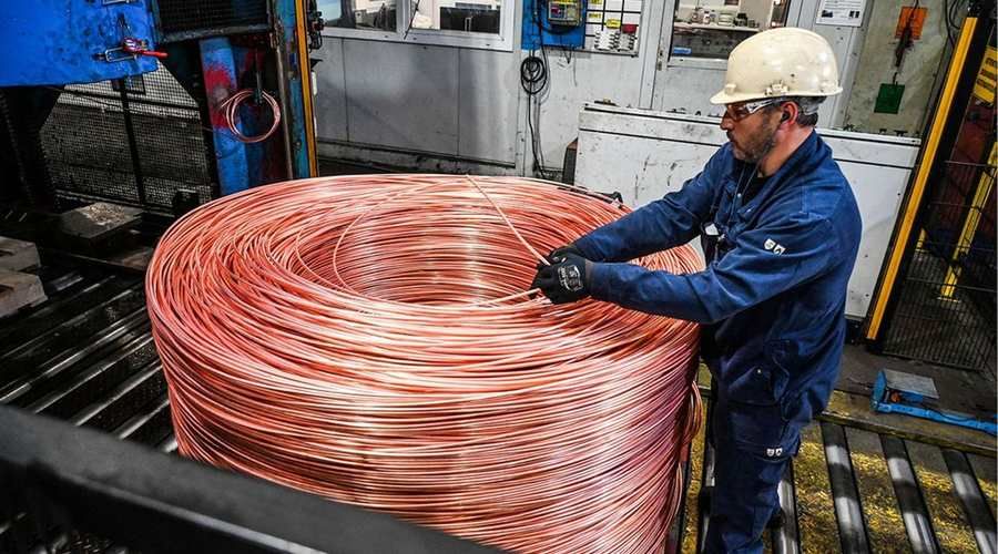 Un technicien manipule une bobine de fil de cuivre en usine